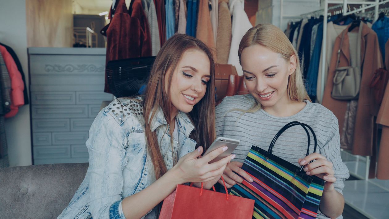 Two shoppers looking at a smartphone inside a clothing store